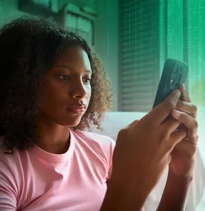 Une adolescente est assise et regarde son cellulaire.